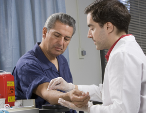 Healthcare provider taking blood from man's arm.